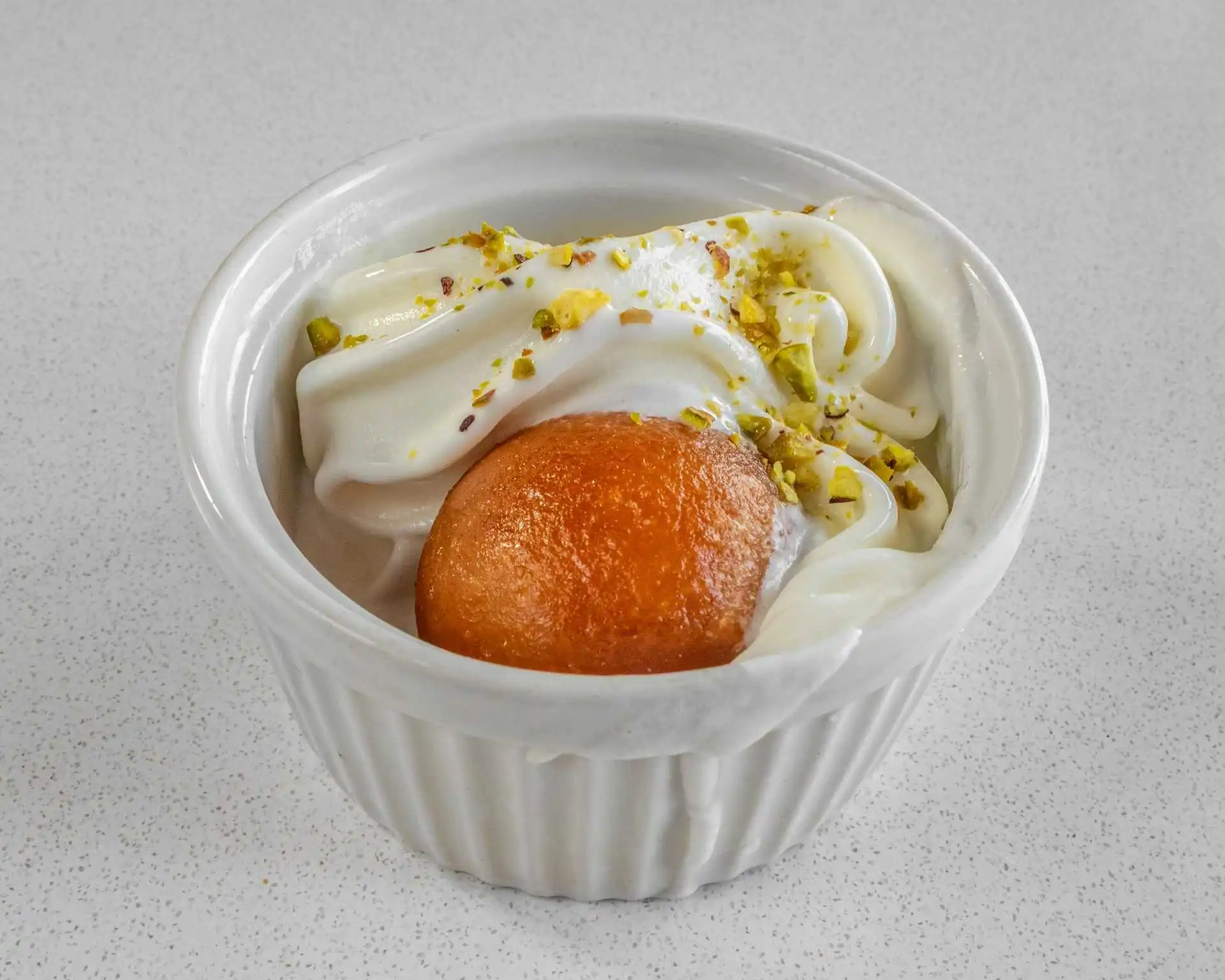 Gulab jamun Indian dessert with cream and pistachio at Charisma Of India Winnipeg